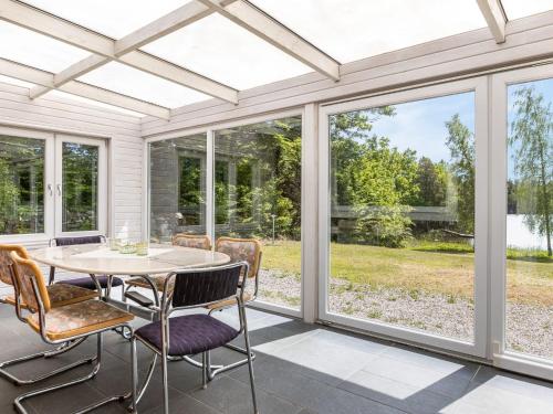 a screened porch with a table and chairs and windows at Holiday Home Erikstorp Femman - B in Olofström