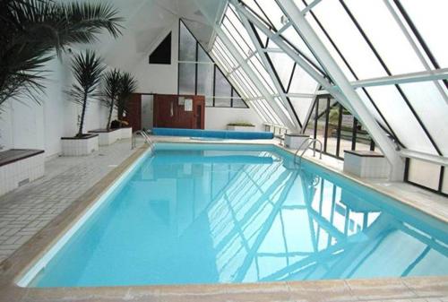une grande piscine avec de l'eau bleue dans un immeuble dans l'établissement Balcon sur Sea, Sun and Horses, à Deauville
