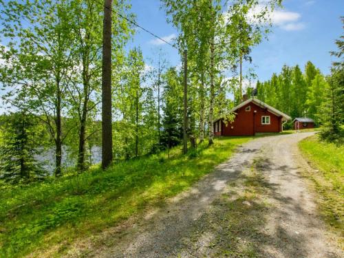 uma estrada de terra que leva a uma cabana vermelha na floresta em Holiday Home Cjoe239 by Interhome em Pölläkkä