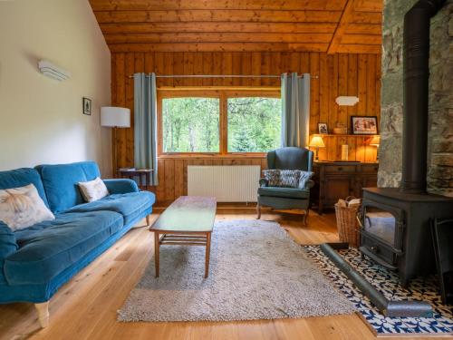a living room with a blue couch and a stove at Holiday Home Kerrow Cottage by Interhome in Inverness