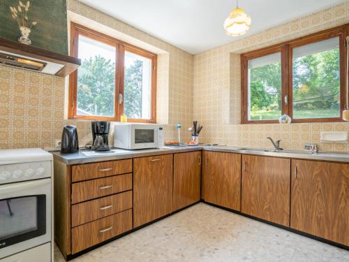 - une cuisine avec des placards en bois et un four micro-ondes blanc dans l'établissement Holiday Home Ker Vian by Interhome, à Tréflez