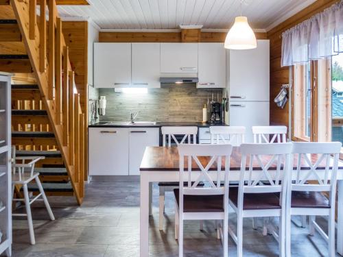 eine Küche mit weißen Schränken und einem Holztisch und Stühlen in der Unterkunft Holiday Home Vuokatin alma by Interhome in Vuokatti