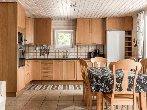 a kitchen with a table with chairs and a refrigerator at Holiday Home Erikstorp Trean - B in Olofström