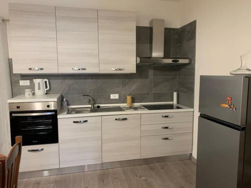 cocina con armarios blancos y nevera de acero inoxidable en La Residenza del Centro, en Padenghe sul Garda