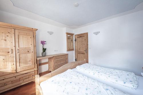 a bedroom with a bed and a wooden cabinet at Kofler zw den Wänden Apt Enzian in Campo Tures