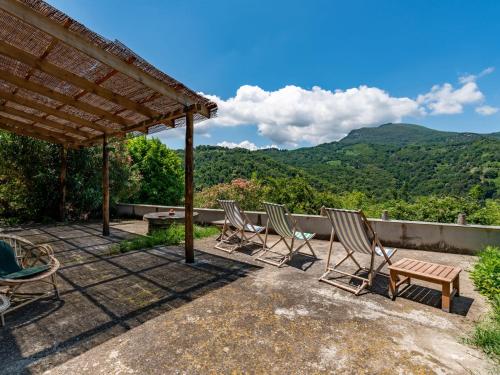 d'une terrasse avec des chaises et une table avec des montagnes en arrière-plan. dans l'établissement Holiday Home Maison Penta by Interhome, à Penta-di-Casinca
