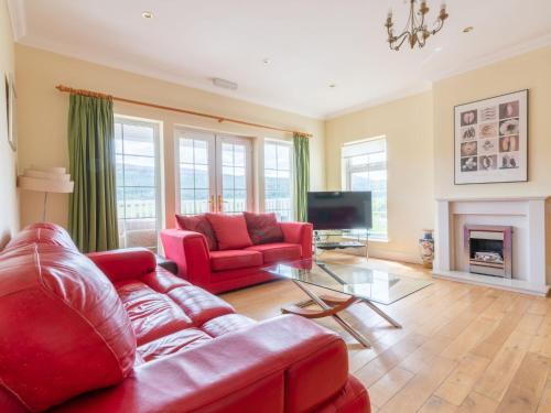 a living room with a red couch and a tv at Holiday Home Bearnock House by Interhome in Drumnadrochit