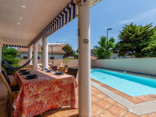 um pátio com uma mesa e uma piscina em Holiday Home Corsaires by Interhome em Vieux-Boucau-les-Bains