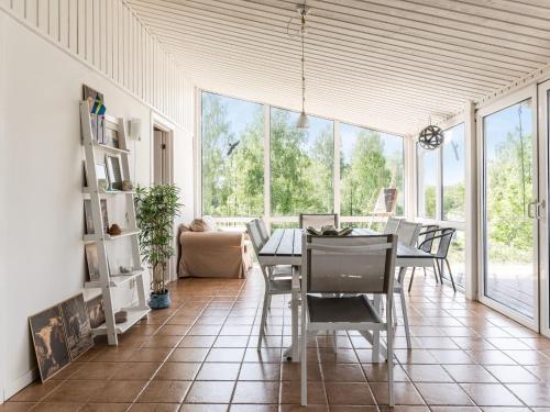 - un salon avec une table, des chaises et des fenêtres dans l'établissement Holiday Home Erikstorp Villan by Interhome, à Olofström