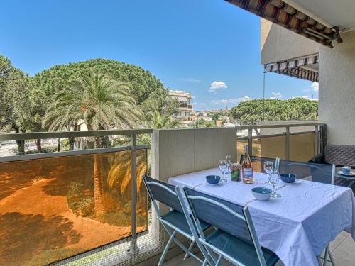 a table with blue chairs and wine glasses on a balcony at Apartment Les Jardins de Phebus by Interhome in Fréjus