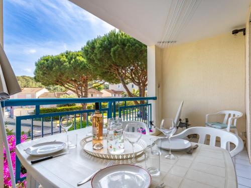 une table avec des assiettes et des verres sur un balcon dans l'établissement Apartment Le Domaine d'Azur-3 by Interhome, au Lavandou