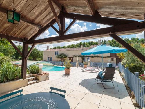 une terrasse avec une table, un parasol et une piscine dans l'établissement Holiday Home Au bord du canal by Interhome, à Mauzé-sur-le-Mignon