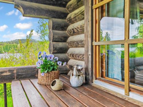 um alpendre de uma cabana de madeira com flores e uma janela em Holiday Home Sinisorsa by Interhome em Rutalahti