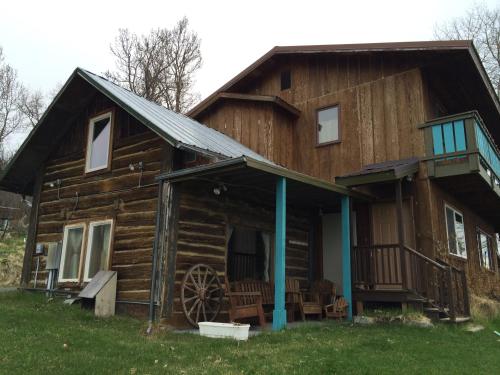 an old log cabin with a porch and a wheel at Homer Stay and Play in Homer