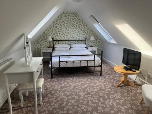 a bedroom with a bed and a desk and a television at Penny Farthing Hotel & Cottages in Lyndhurst