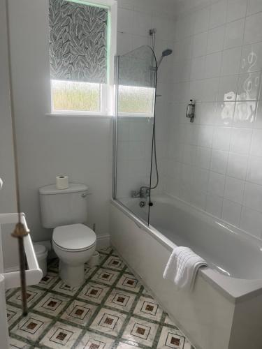 a bathroom with a tub and a toilet and a window at Penny Farthing Hotel & Cottages in Lyndhurst