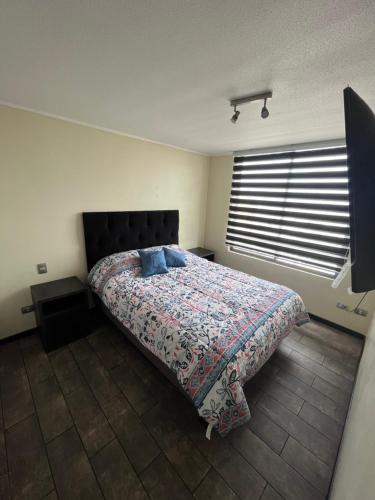 a bedroom with a bed with a blanket and a window at Elegante departamento in Iquique