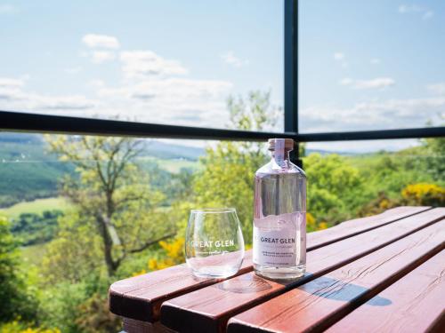 a bottle sitting on a wooden table with a glass at Holiday Home Achmony Type 2-3 by Interhome in Drumnadrochit