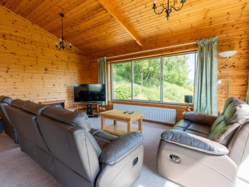 a living room with leather furniture and a large window at Holiday Home Achmony Type 2-3 by Interhome in Drumnadrochit