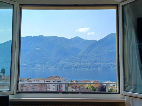 een raam met uitzicht op het water en de bergen bij Apartment Residenza Aviva by Interhome in Muralto