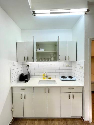 a kitchen with white cabinets and a sink at Bat Galim BEACH apartment in Haifa