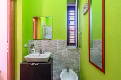 een groene badkamer met een wastafel en een spiegel bij Villa Franca zona Arenella in Siracusa