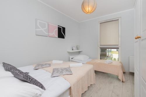 a white room with two beds and a window at Turzycowa Apartment in Gdansk by Renters in Gdańsk