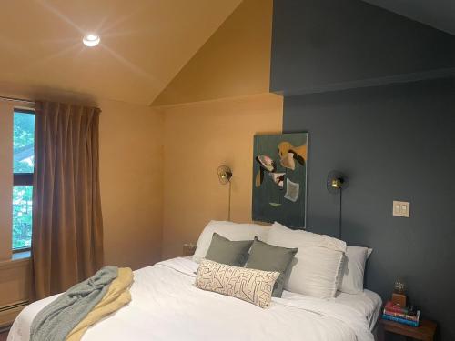 una camera da letto con letto, lenzuola e cuscini bianchi di The Trail in Adams - Berkshires' Art Hotel ad Adams