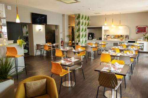 a restaurant with tables and chairs and a kitchen at HÔTEL LE CHAPON FIN in Moissac