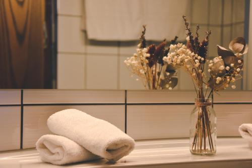 a bathroom counter with a vase of flowers and a towel at Hotel Bahnhof in Giswil
