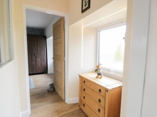 a room with a wooden dresser and a window at Braeface Cottage in Bonnybridge