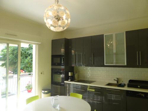 une cuisine avec une table blanche et un lustre dans l'établissement SUPERBE VILLA - MODERNE sur JARDIN 15 Mn de Paris, à Le Perreux-Sur-Marne