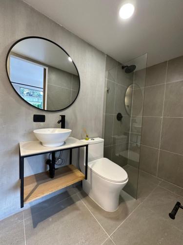 a bathroom with a sink and a toilet and a mirror at Hotel Santa Ana Medellin in Medellín