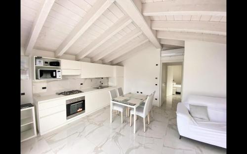 eine weiße Küche mit einem Tisch und einem Esszimmer in der Unterkunft Superior apt Colico Lake Como in Colico