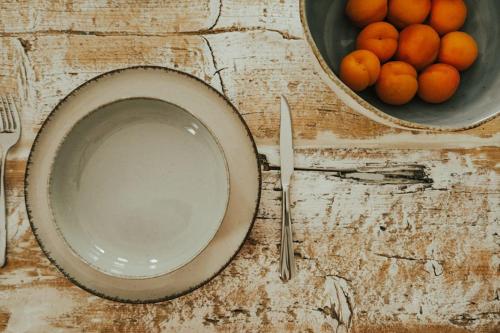 a table with a bowl of oranges and a bowl of plates and a bowl at Sol living in Tinos