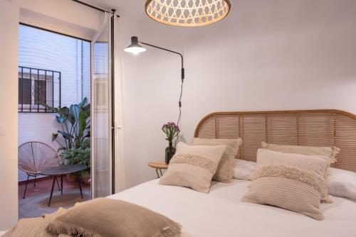 1 dormitorio con 1 cama con sábanas y almohadas blancas en apartamentos junto a jardines del triunfo en Granada