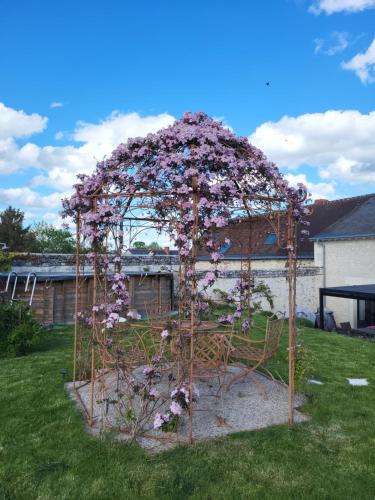 a garden arch covered in purple flowers in a yard at Chez Onna in Theneuil