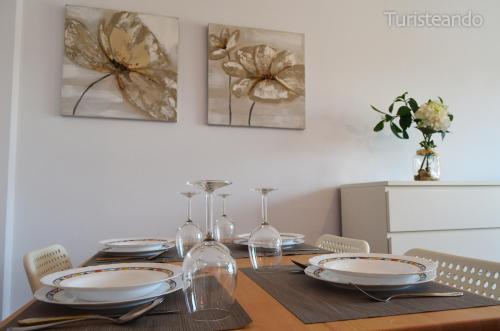 a dining room table with plates and wine glasses at Apartamento La Barquera - Muy acogedor con vistas a la Ría in San Vicente de la Barquera