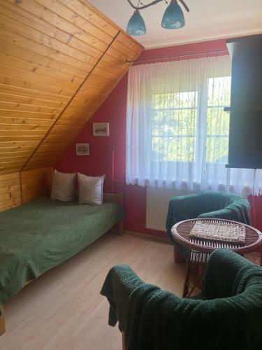 a room with two beds and a table and a window at Przed Korzeniowym in Kazimierz Dolny