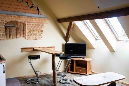 a room with a desk with stools and a television at Schwalbenwohnung 