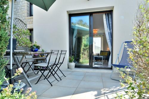 d'une terrasse avec des chaises, une table et une porte en verre. dans l'établissement Cap Frehel gîte 4 personnnes, à Fréhel