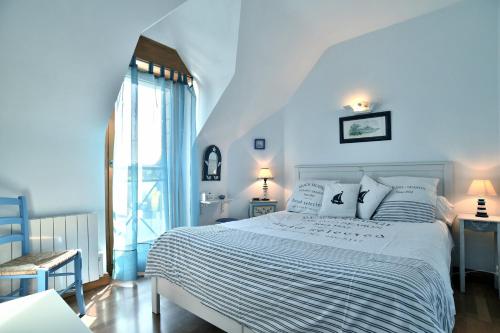 um quarto azul com uma cama branca e uma janela em Cap Frehel gîte 4 personnnes em Frehel