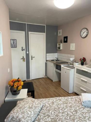 Cet appartement comprend une chambre avec un lit et une cuisine avec une horloge. dans l'établissement Studio Montsouris, à Paris
