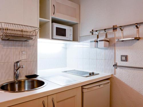 eine Küche mit einer Spüle und einer Mikrowelle in der Unterkunft Studio Brides-les-Bains, 1 pièce, 4 personnes - FR-1-512-156 in Brides-les-Bains