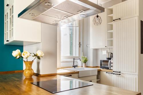 a kitchen with white cabinets and a vase of flowers on a table at ALTIDO Delightful flat with terrace in Milan