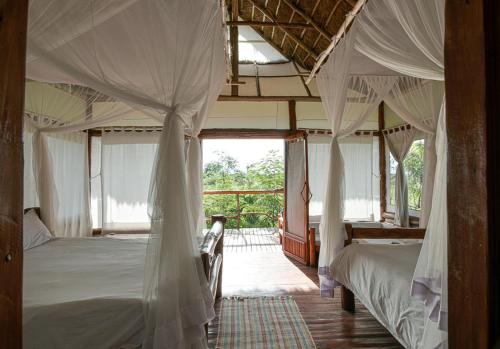 a bedroom with two beds and a large window at Kazinga Wilderness Safari Camp in Kasese