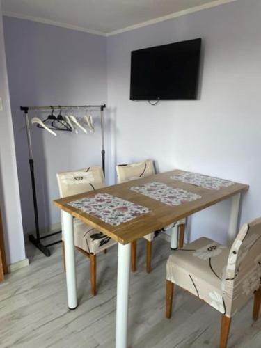stół jadalny z krzesłami i telewizor na ścianie w obiekcie Pokoje Kościelna 6 w Supraślu
