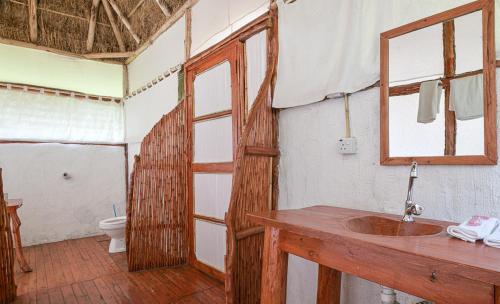 a bathroom with a wooden sink and a toilet at Kazinga Wilderness Safari Camp in Kasese