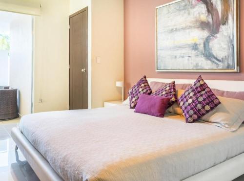 1 dormitorio con 1 cama grande con almohadas moradas en 2 BR Apartment - Pool & jacuzzi, en Cancún