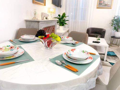 un tavolo bianco con piatti e una ciotola di frutta di Perle d'Azur: Raffinement unique a Grasse